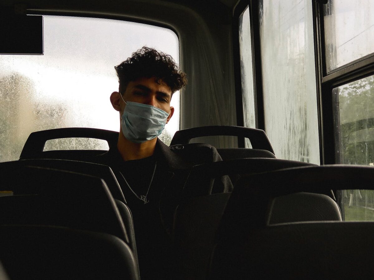 serious young man in protective mask in bus