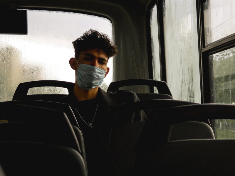 serious young man in protective mask in bus