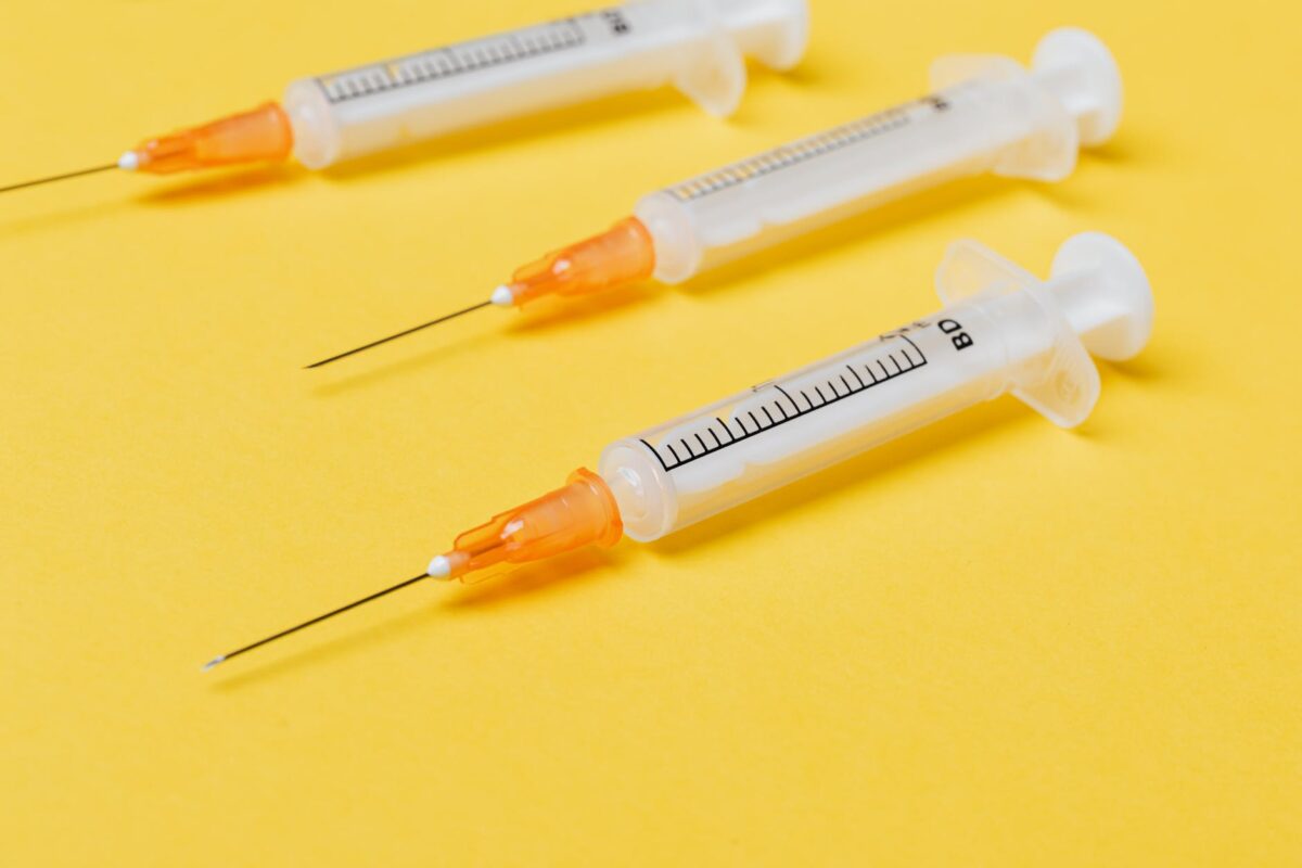 empty syringe injectors on yellow background