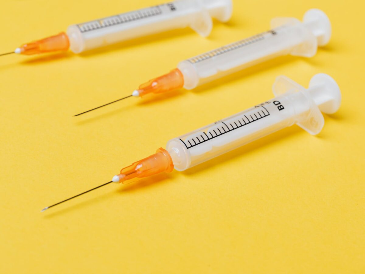 empty syringe injectors on yellow background