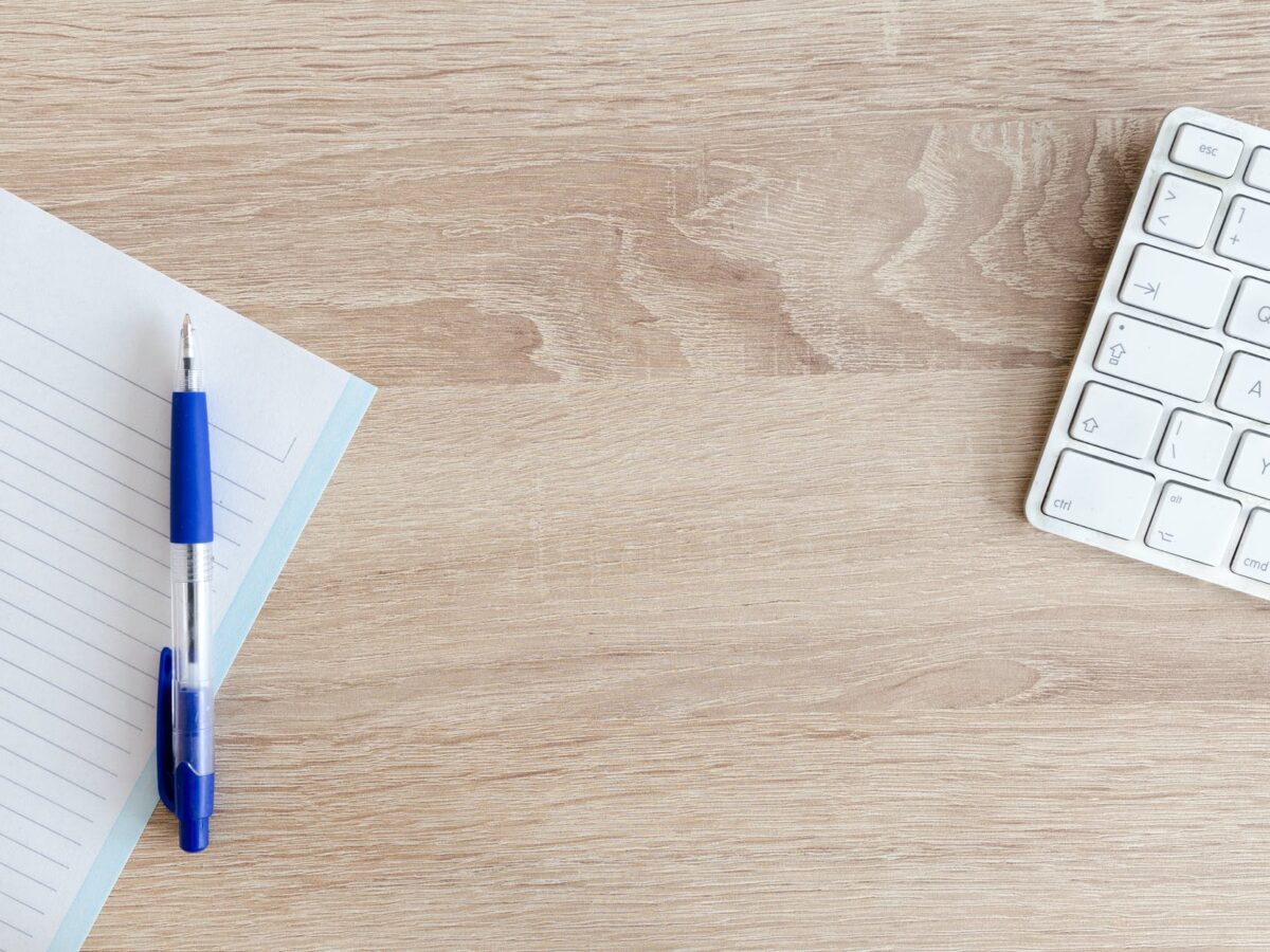 blue retractable pen on top of notebook near magic keyboard